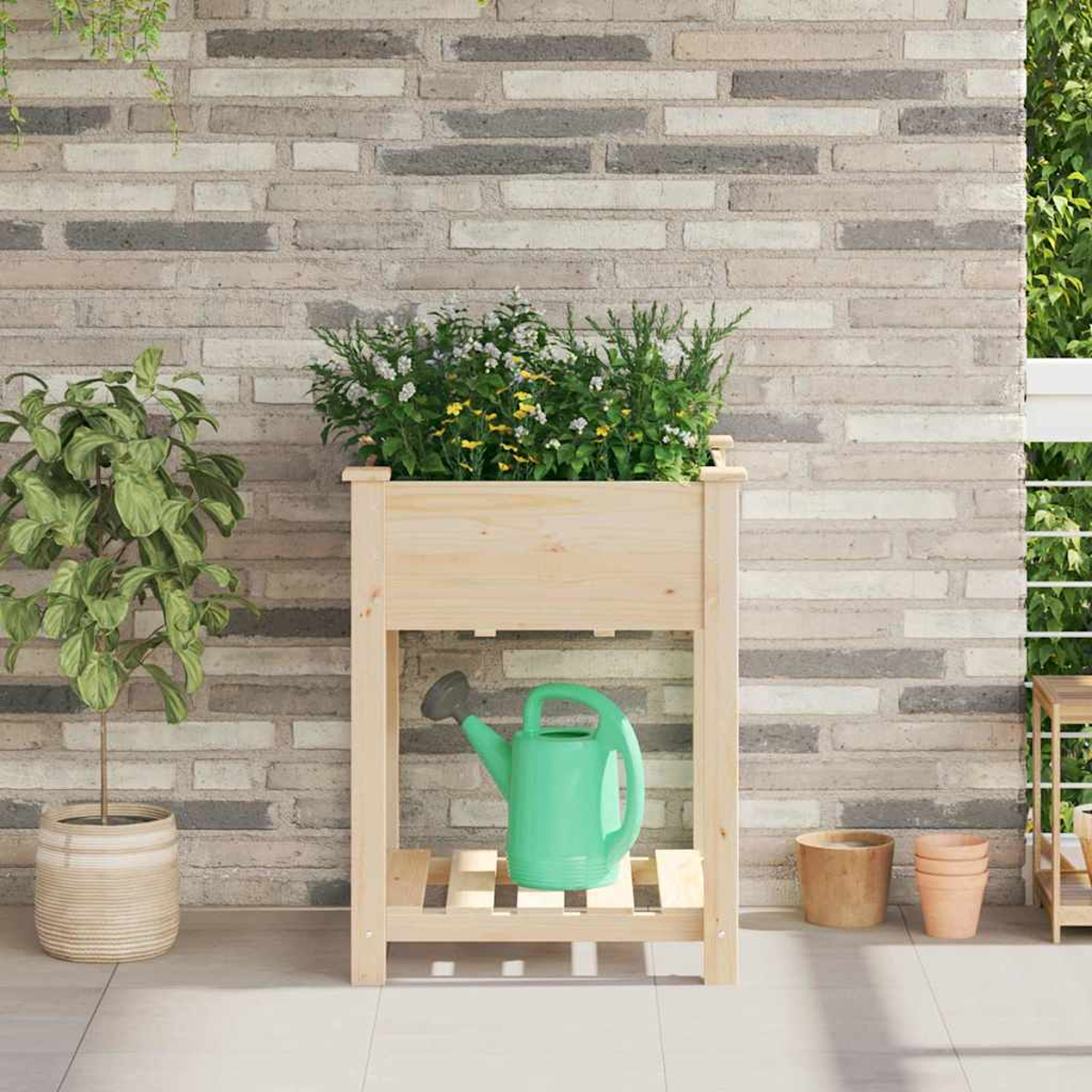 Una fioriera di legno piena di piante. Un annaffiatoio verde sotto. Un muro di mattoni sullo sfondo.