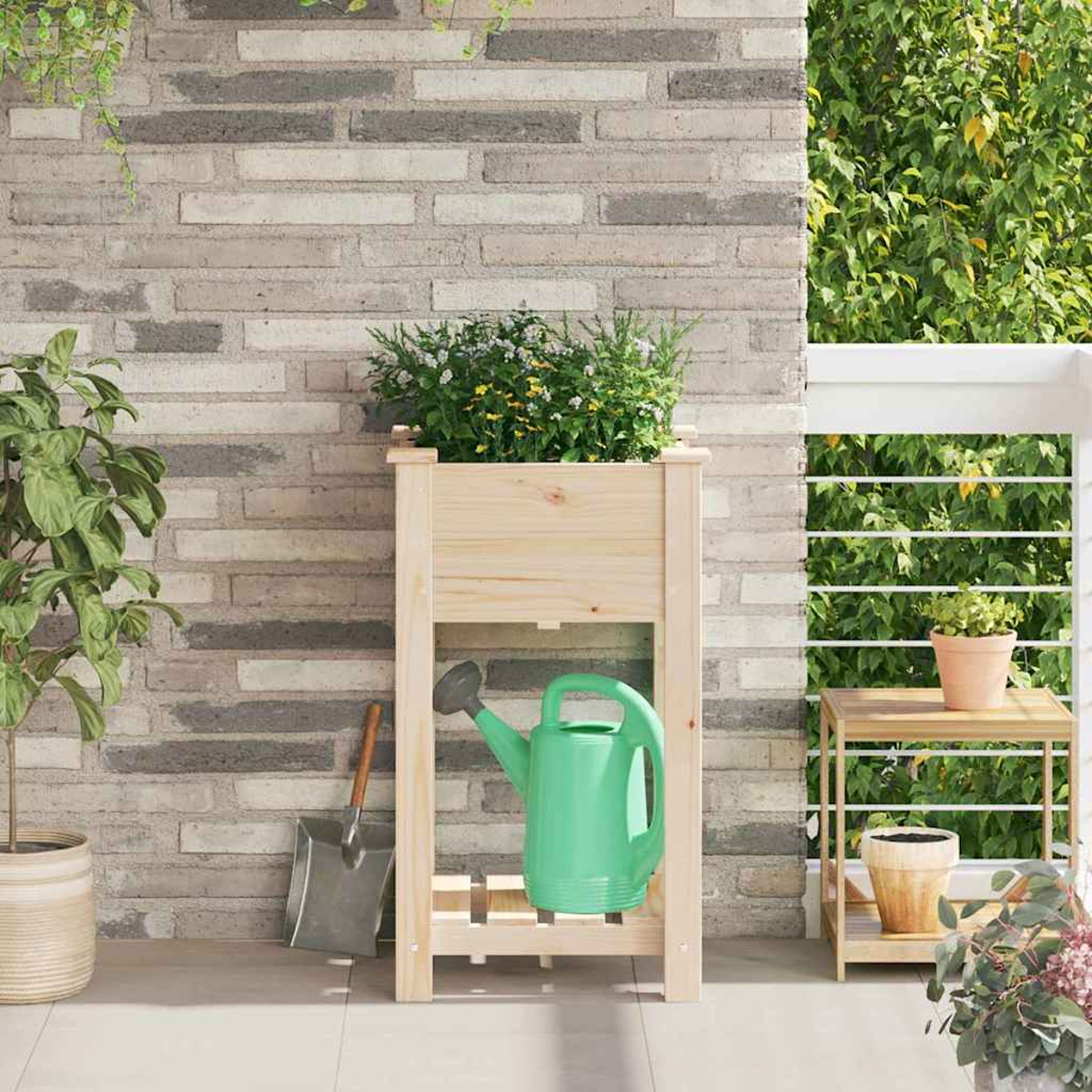 Fioriera in legno con piante, un annaffiatoio verde, una pala e un tavolino con un vaso. Lo sfondo è un muro di mattoni e verde.