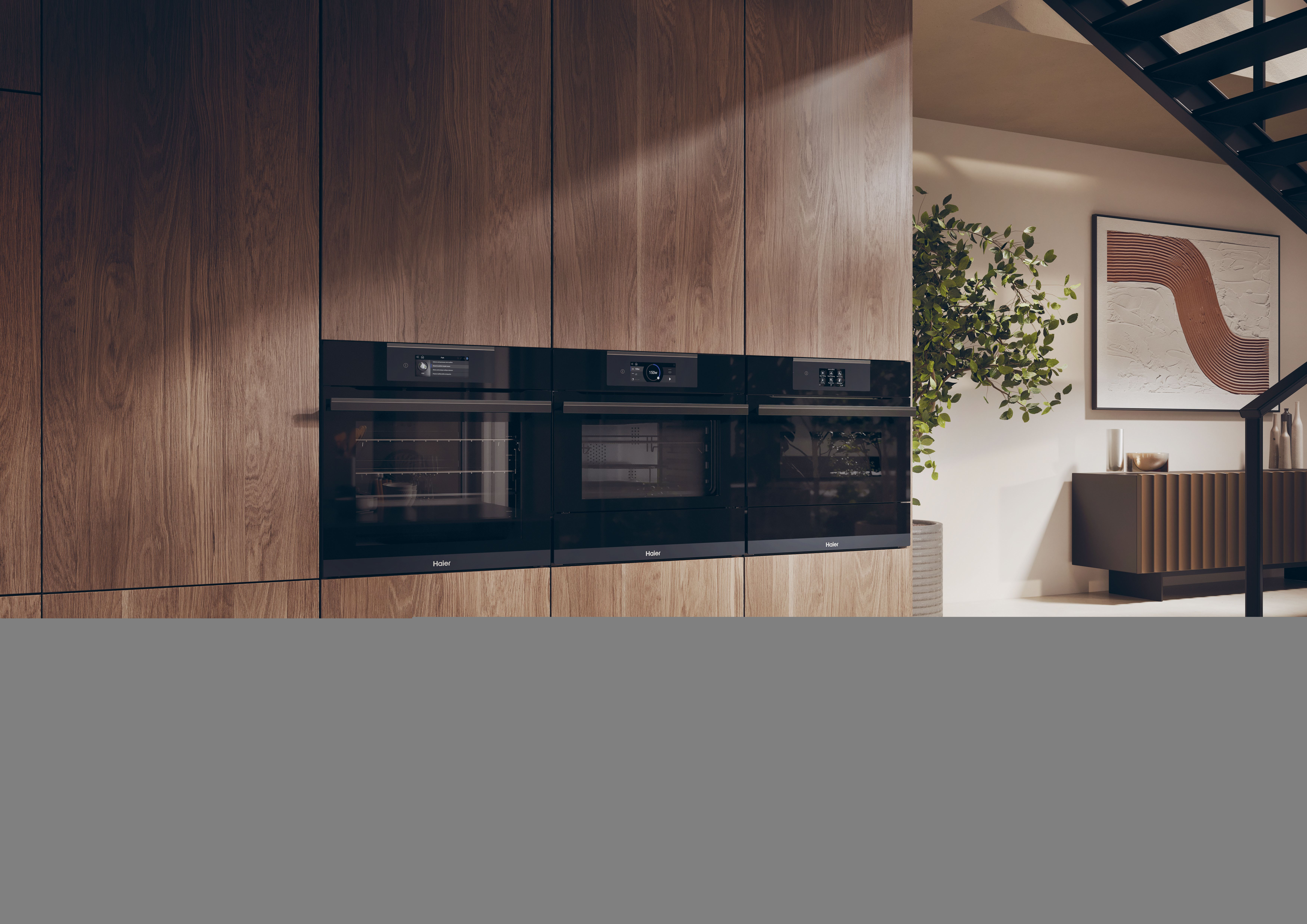Cocina moderna con gabinetes de madera. Hornos empotrados con pantallas digitales. Fondo: planta, obra de arte, escaleras y gabinete.