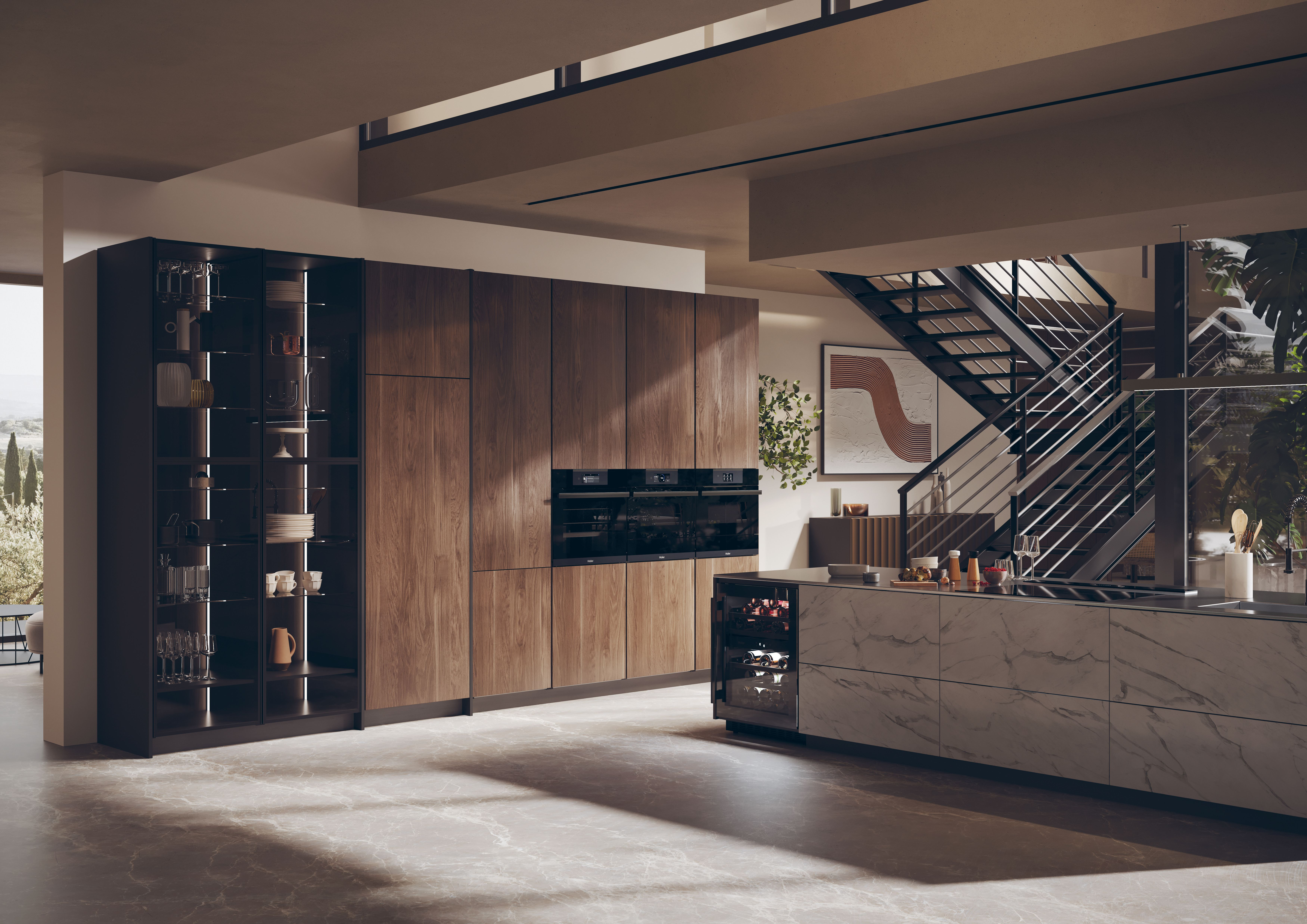 Cocina moderna con gabinetes de madera, encimeras de mármol y escalera al fondo. Visible vitrina de cristal y nevera de vinos.