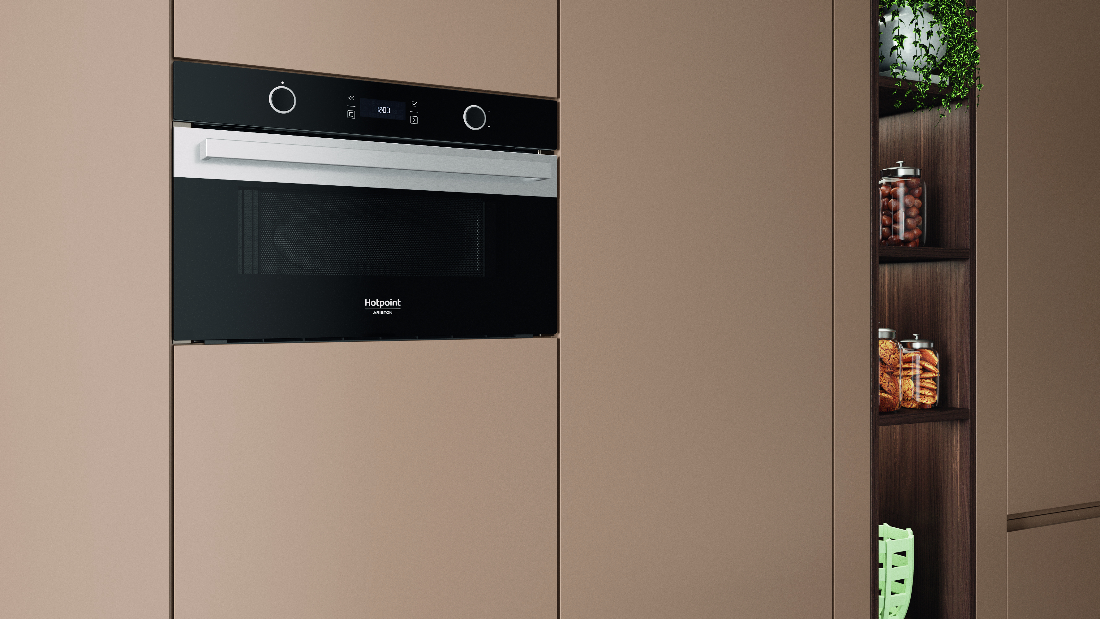 Un forno Hotpoint a incasso è centrato su un mobile beige. Un armadio a destra contiene barattoli e una pianta.