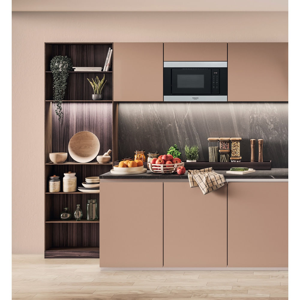 Moderne keuken met magnetron, fruit en houten planken. Kastdeuren en houten vloer. Appels, sinaasappels en kruiden op het aanrecht.