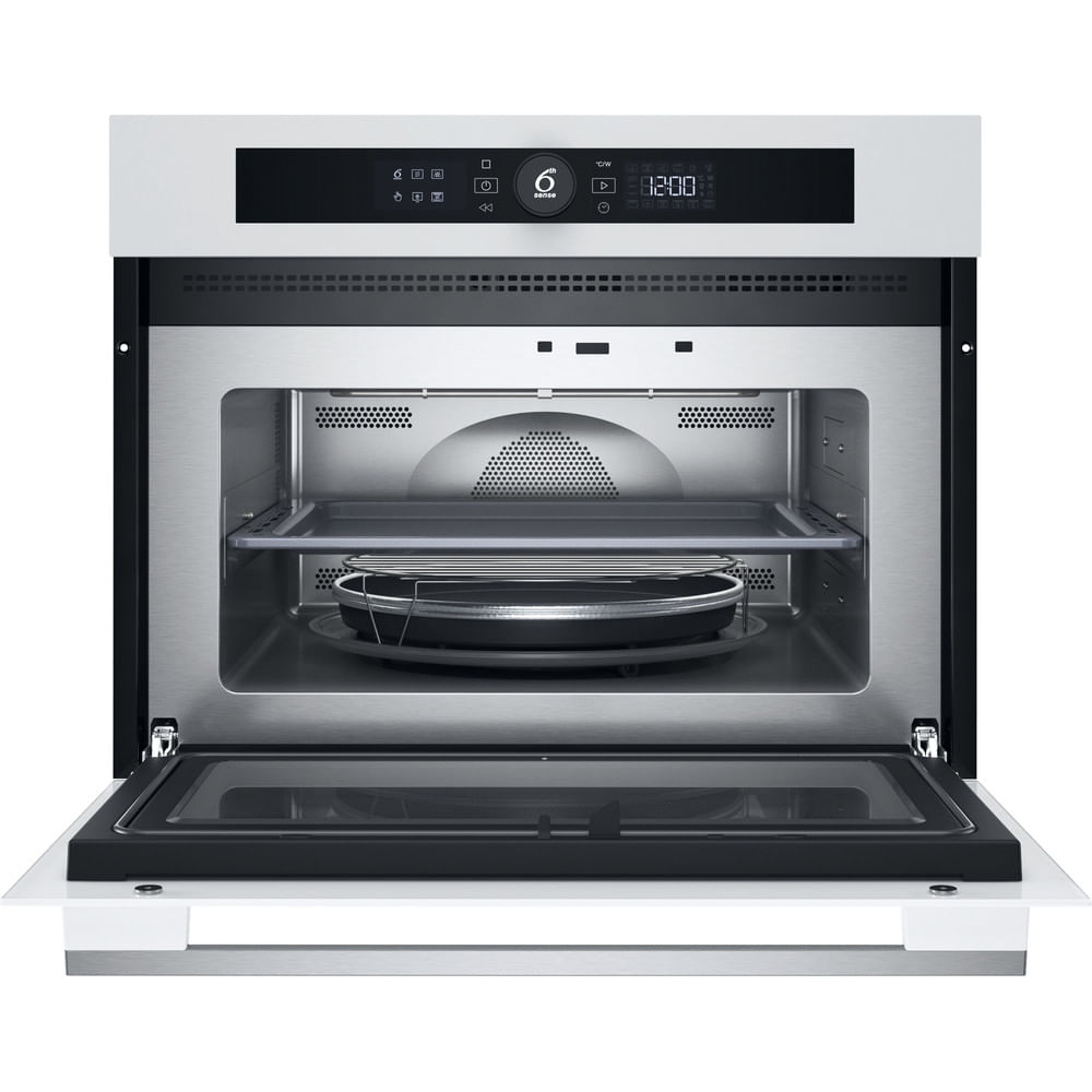 Un forno a microonde bianco con la porta aperta. All'interno ci sono vassoi e una griglia. Il display mostra l'ora.