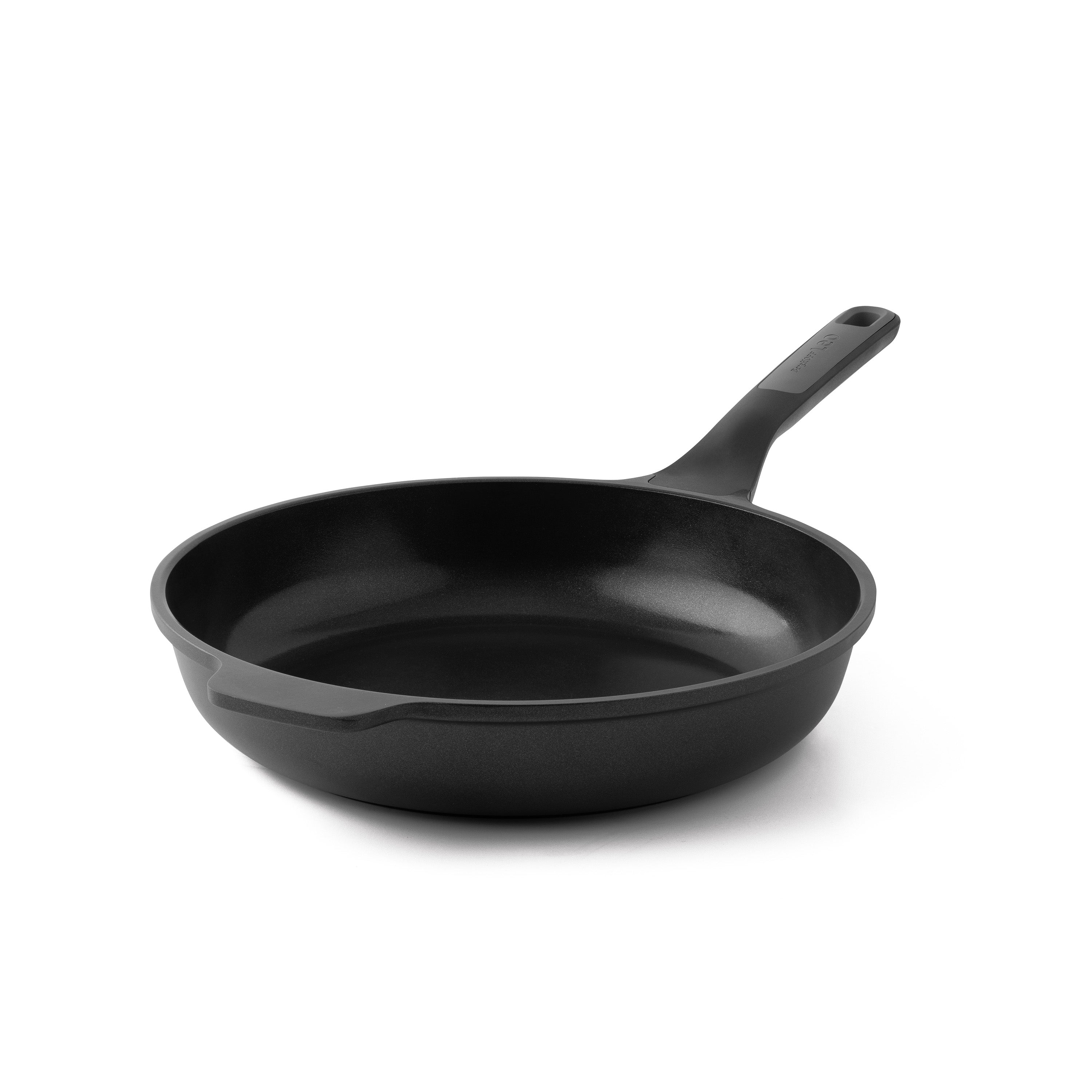 Een zwarte koekenpan met een handvat op een witte achtergrond. De pan is rond en leeg.