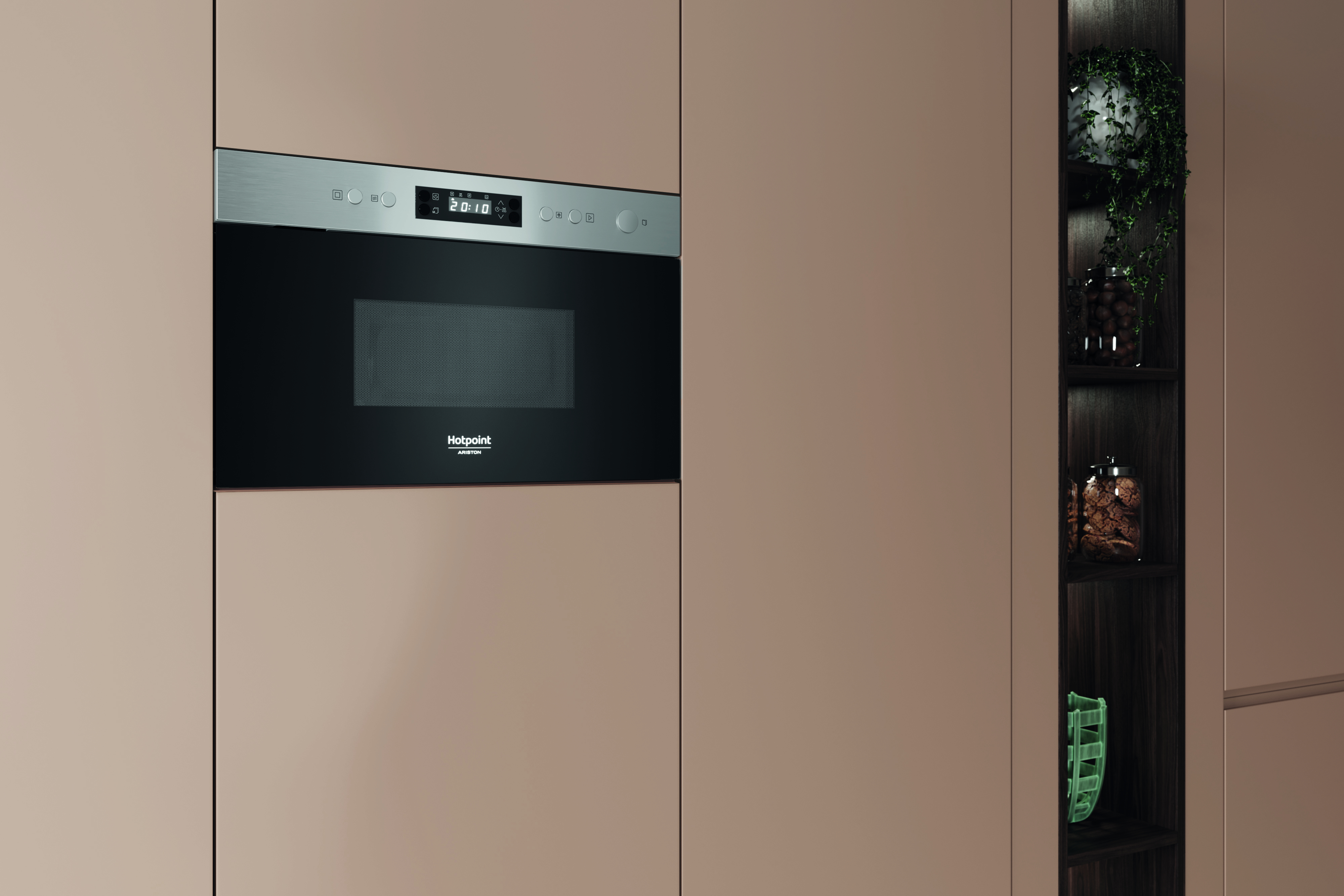 Un horno microondas empotrado con pantalla digital y un armario con estantes. Se ven tarros con galletas y plantas.