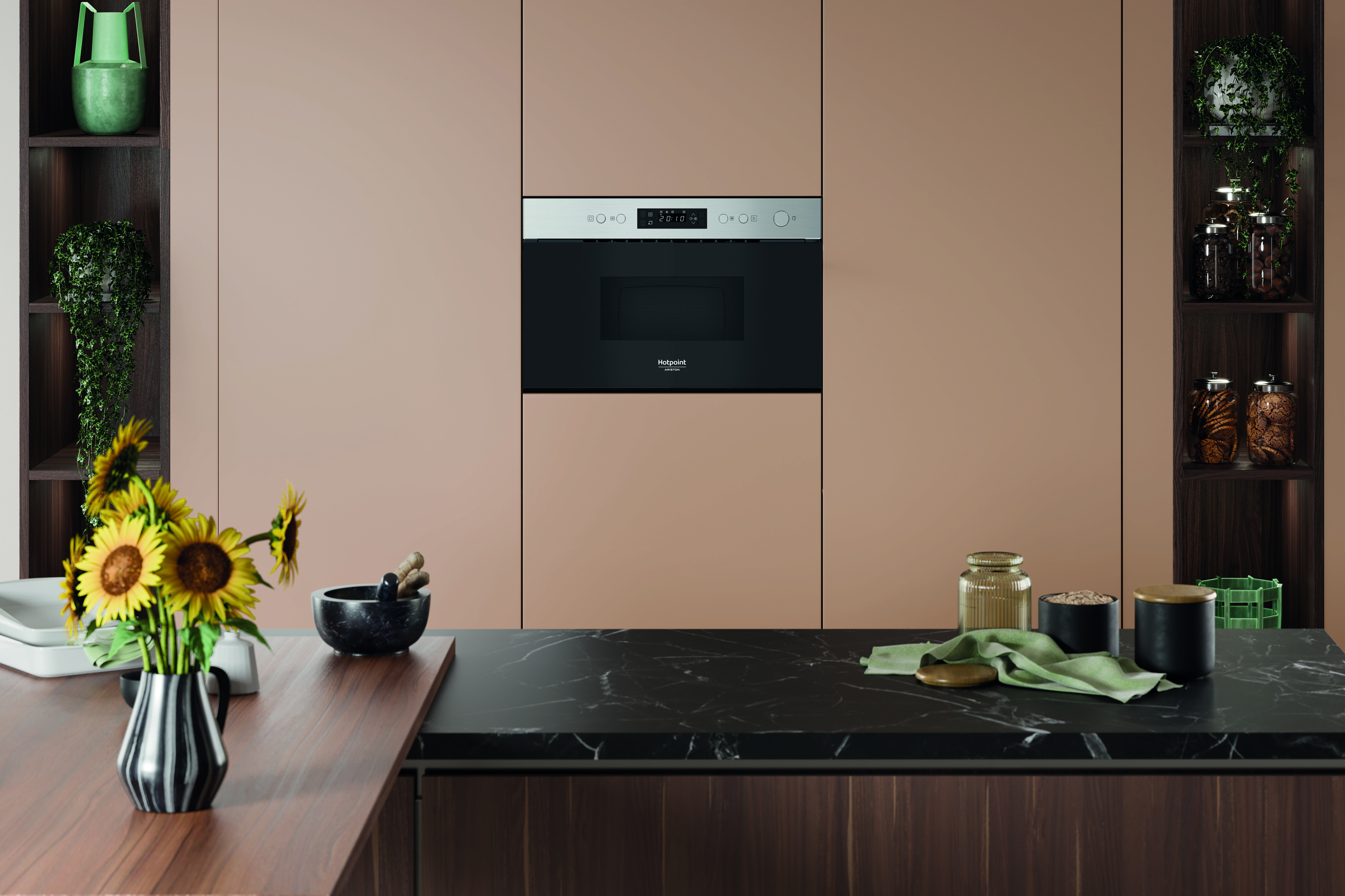 Una cocina moderna con microondas, girasoles y varias decoraciones en la encimera y estanterías.