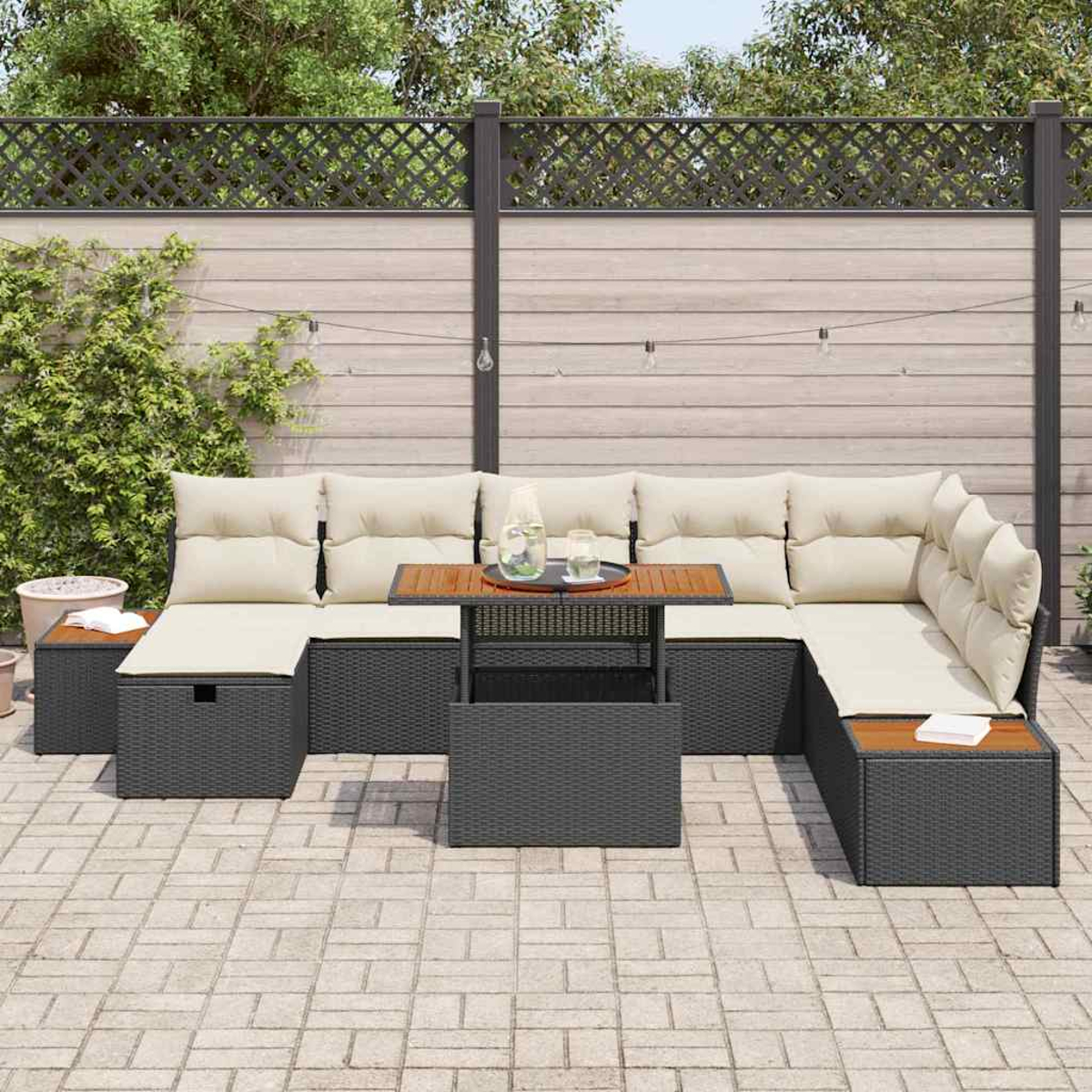 Outdoor-Ecksofa mit hellen Kissen und einem Holztisch auf einer Steinterrasse. Im Hintergrund ein Zaun und Grün.