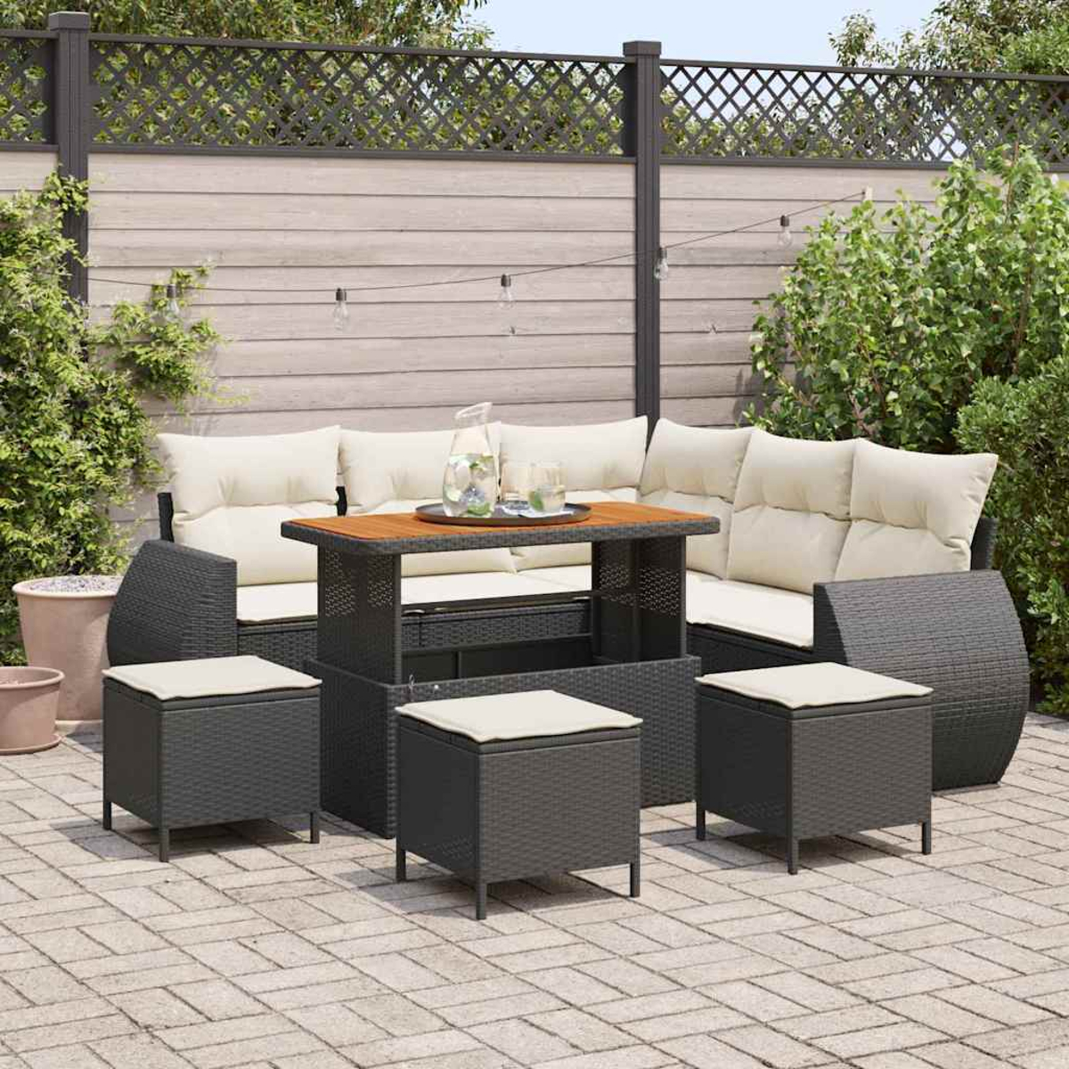 Garten-Terrassenset mit grauen Korbmöbeln, beigen Kissen und einem Holztisch. Das Set steht auf einer Ziegelterrasse mit Holzzaun.