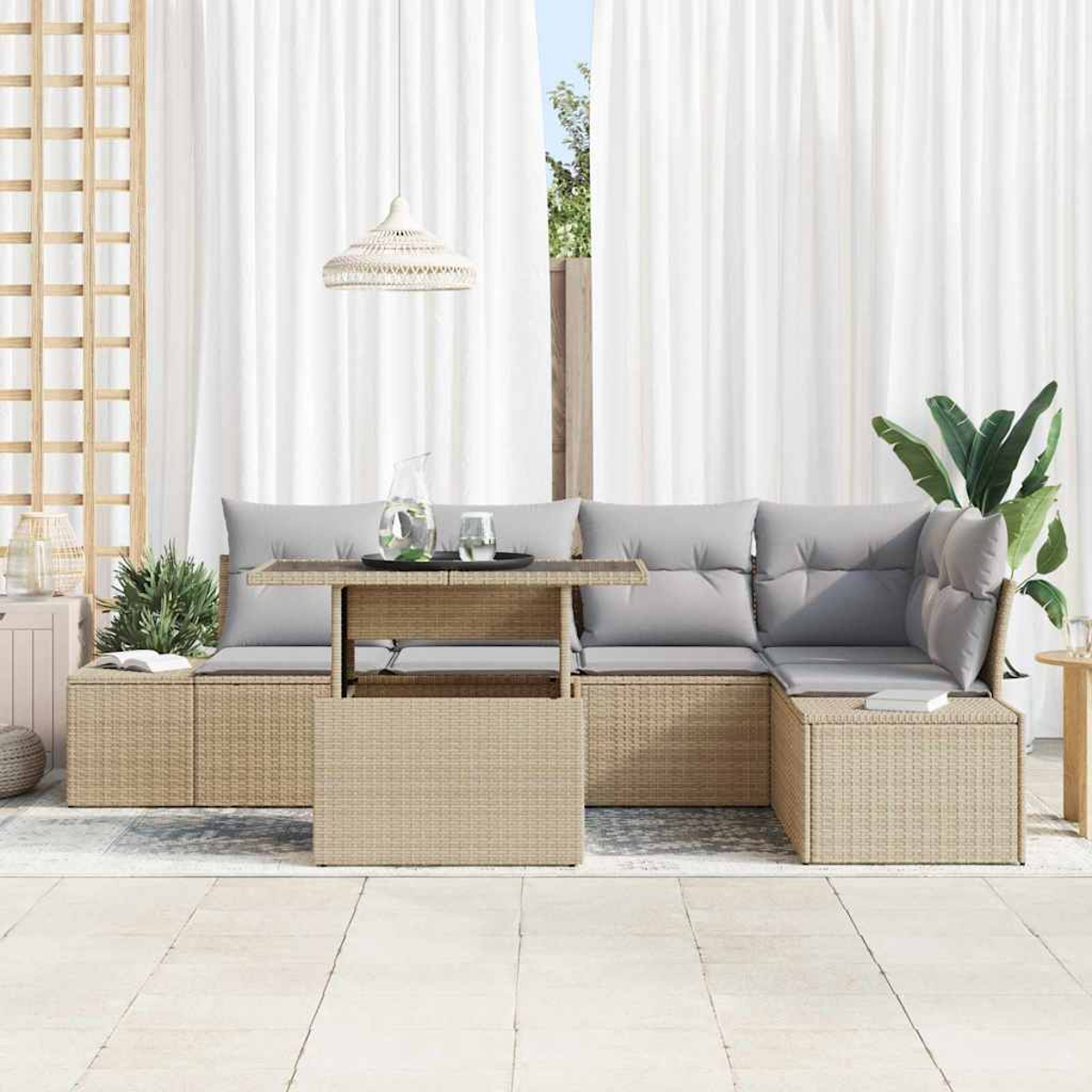 Garten-Sitzgruppe mit hellgrauen Kissen, Untergestell im Rattan-Stil und Tisch. Weiße Vorhänge und Grün im Hintergrund.