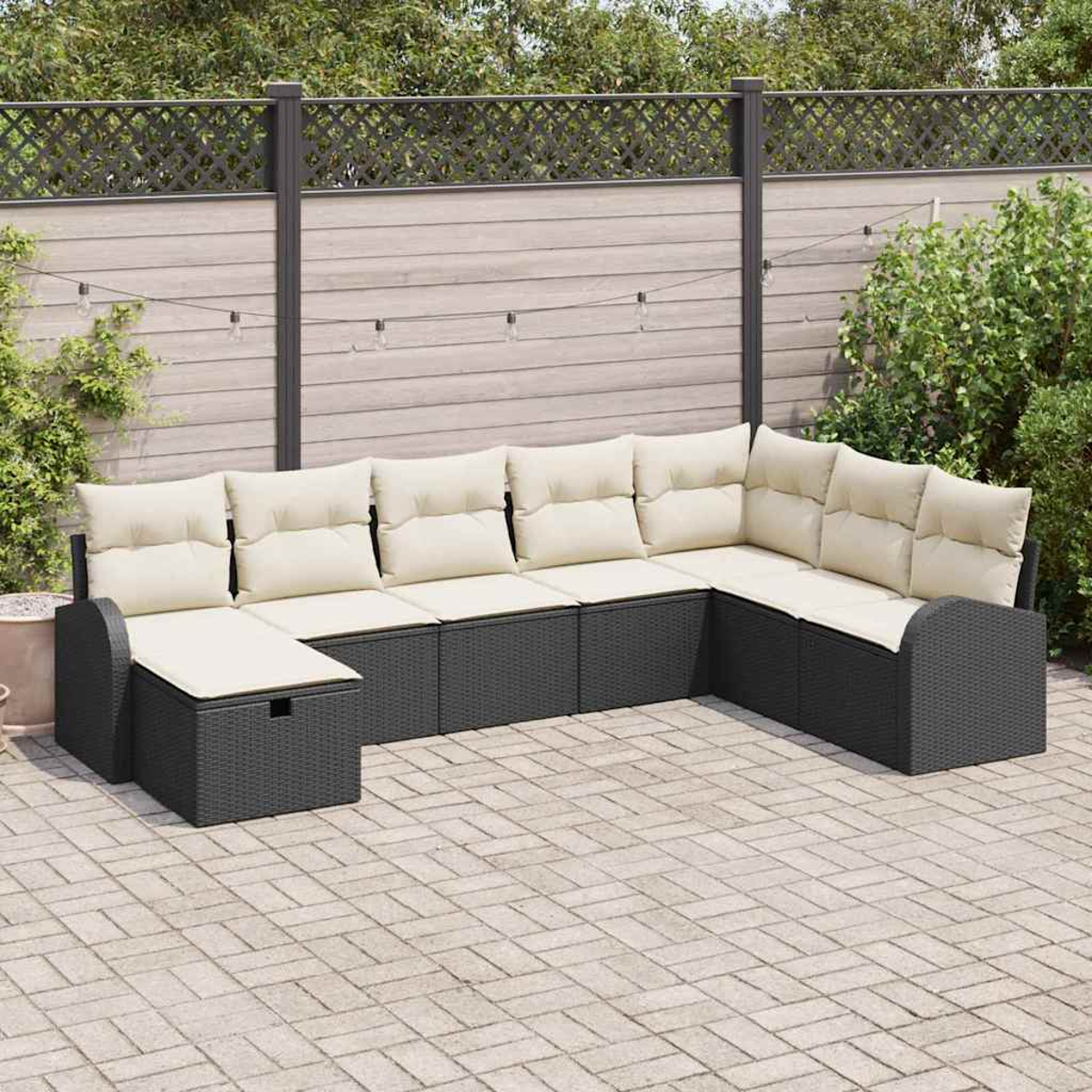 Ein Ecksofa im Freien mit cremefarbenen Kissen steht auf einer Terrasse. Ein Zaun und Grün bilden den Hintergrund. Lichterketten hängen darüber.