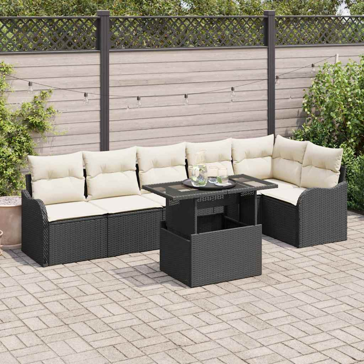 Juego de patio al aire libre con muebles de mimbre negro, cojines crema y mesa elevable. El fondo presenta una valla y vegetación.