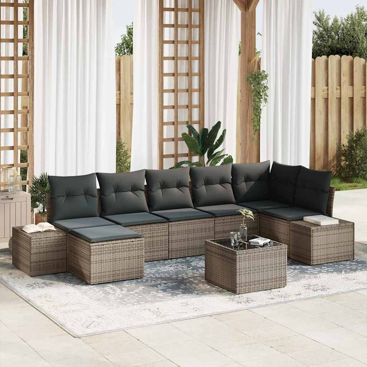 Outdoor-Sitzgruppe auf einer Terrasse. Sie verfügt über ein großes Sofa mit grauen Kissen, einen Couchtisch und einen Teppich. Weiße Vorhänge im Hintergrund.