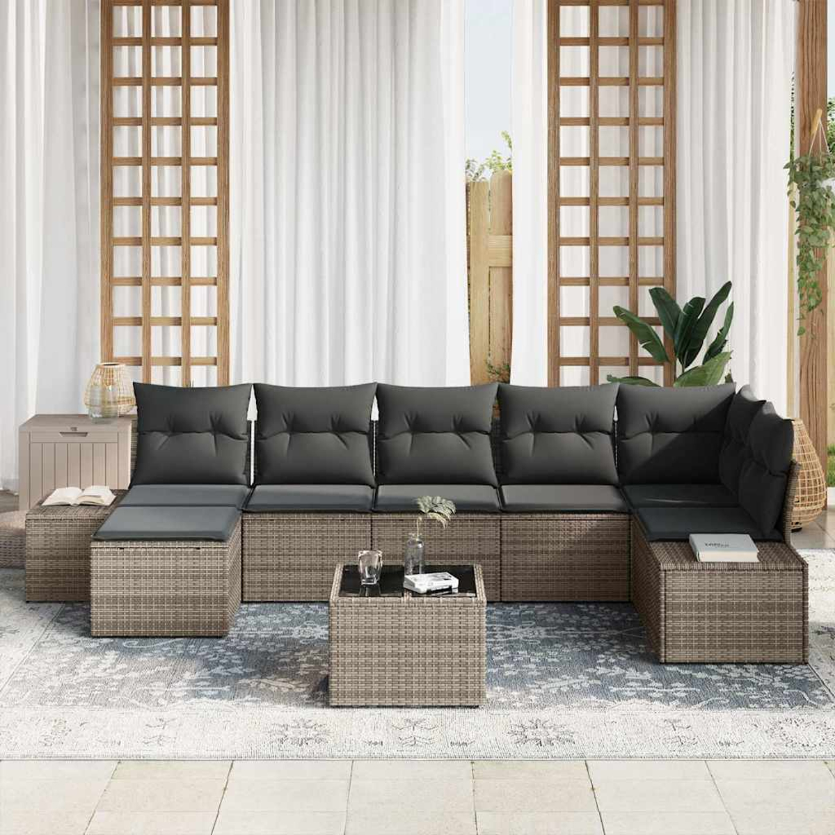 Outdoor-Ecksofa mit grauen Kissen auf einem Teppich, mit Couchtisch. Hintergrund zeigt Fenster und Vorhänge.