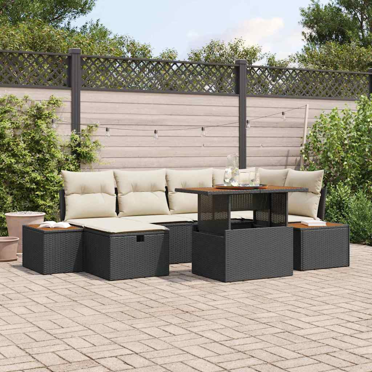 Garten-Sitzgruppe mit beigefarbenen Kissen, einem Tisch und Aufbewahrungshockern. Im Hintergrund ein Holzzaun und Grün.