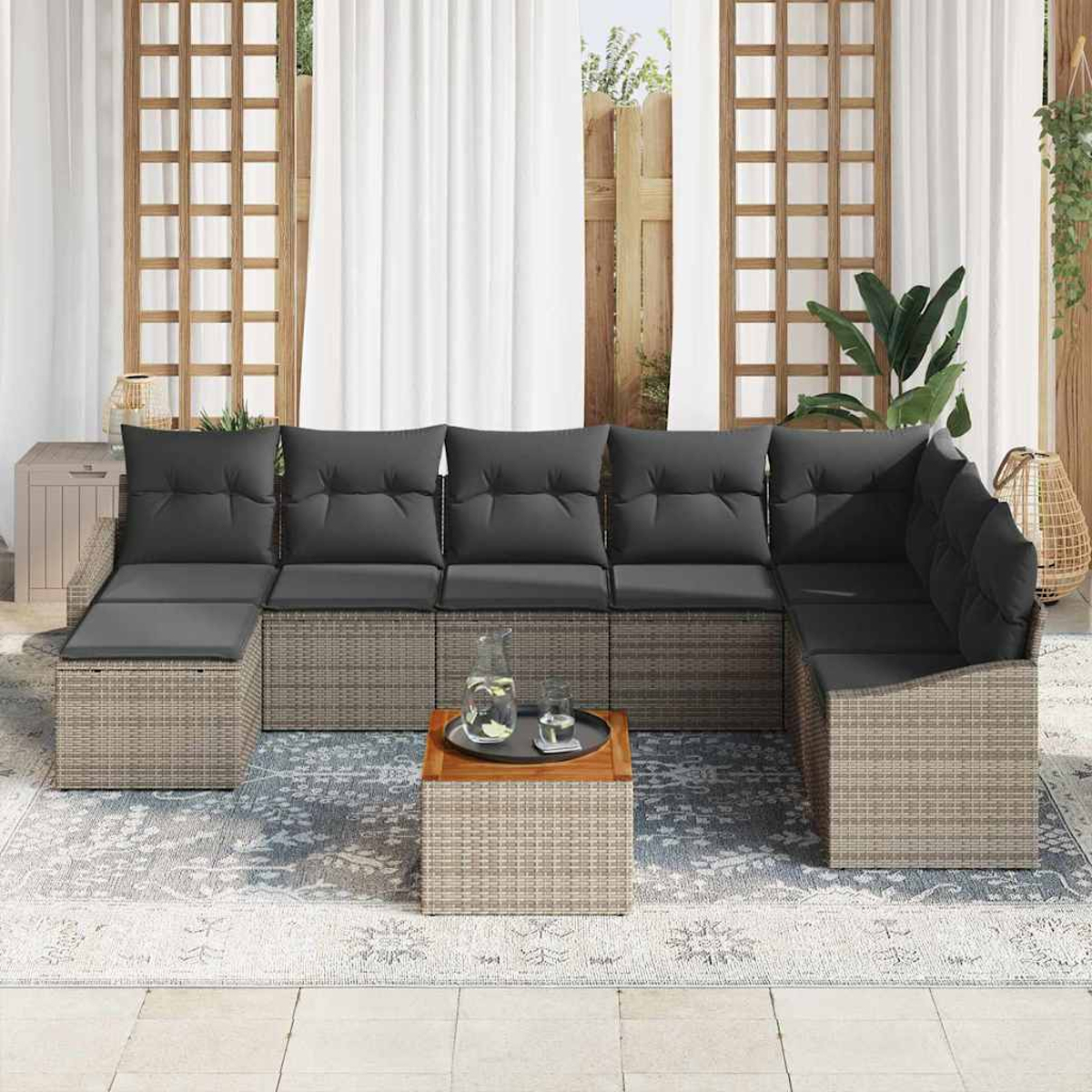 Outdoor-Ecksofa mit grauen Kissen. Ein kleiner Holztisch mit Tablett und Gläsern. Hintergrund: Vorhänge und Pflanzen.