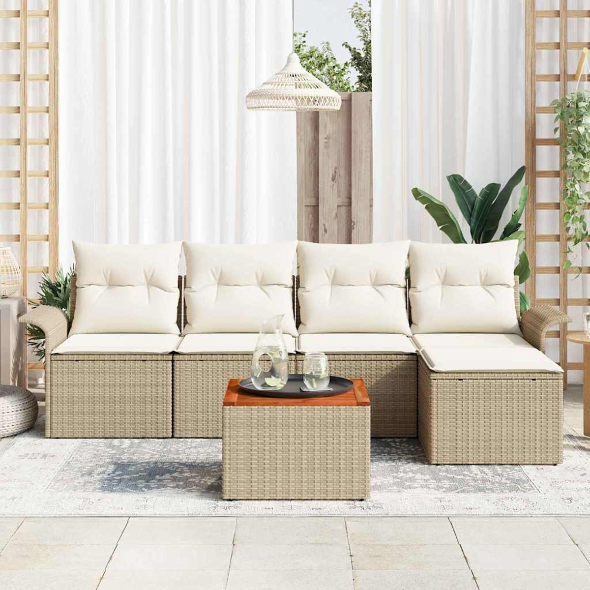 Outdoor-Sitzbereich mit beigen Korbmöbeln, weißen Kissen, einem Couchtisch und weißen Vorhängen im Hintergrund.