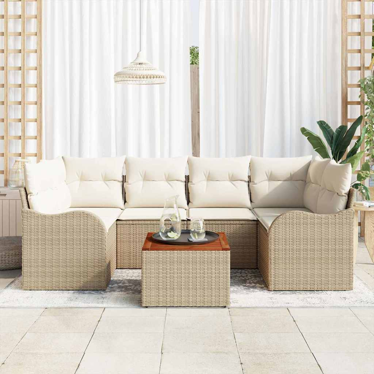 Outdoor-Sitzgruppe mit beigen Kissen und gewebtem Rahmen. Ein Couchtisch hält ein Tablett mit Gläsern und einer Kanne. Weiße Vorhänge im Hintergrund.