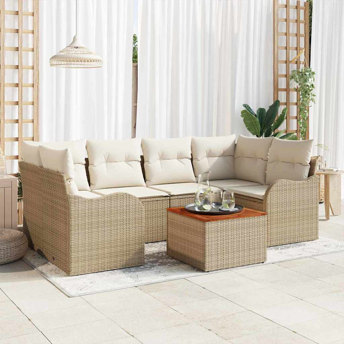 Outdoor-Korbsessel mit cremefarbenen Kissen, Couchtisch mit Getränken, weißen Vorhängen und Hängeleuchte. Eine Pflanze ist sichtbar.