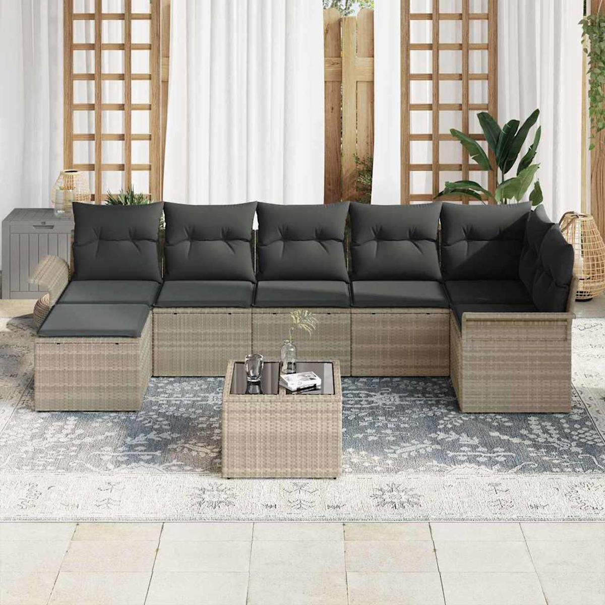 Outdoor-Ecksofa mit grauen Kissen auf einem gemusterten Teppich, kleinem Tisch und Holzgitter-Hintergrund.