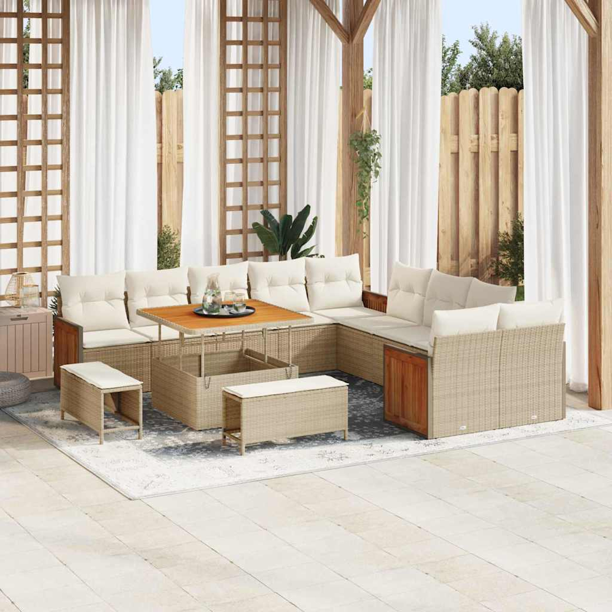 Set da patio esterno con mobili in vimini beige, cuscini bianchi, tavolo e panche in legno. Tende e staccionata in legno.