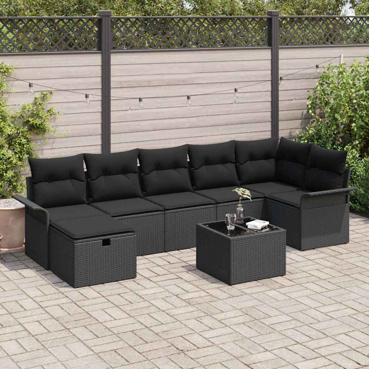 Schwarzes Outdoor-Wicker-Sofaset mit Kissen und Tisch auf einer gepflasterten Terrasse. Ein Zaun und Grün im Hintergrund.