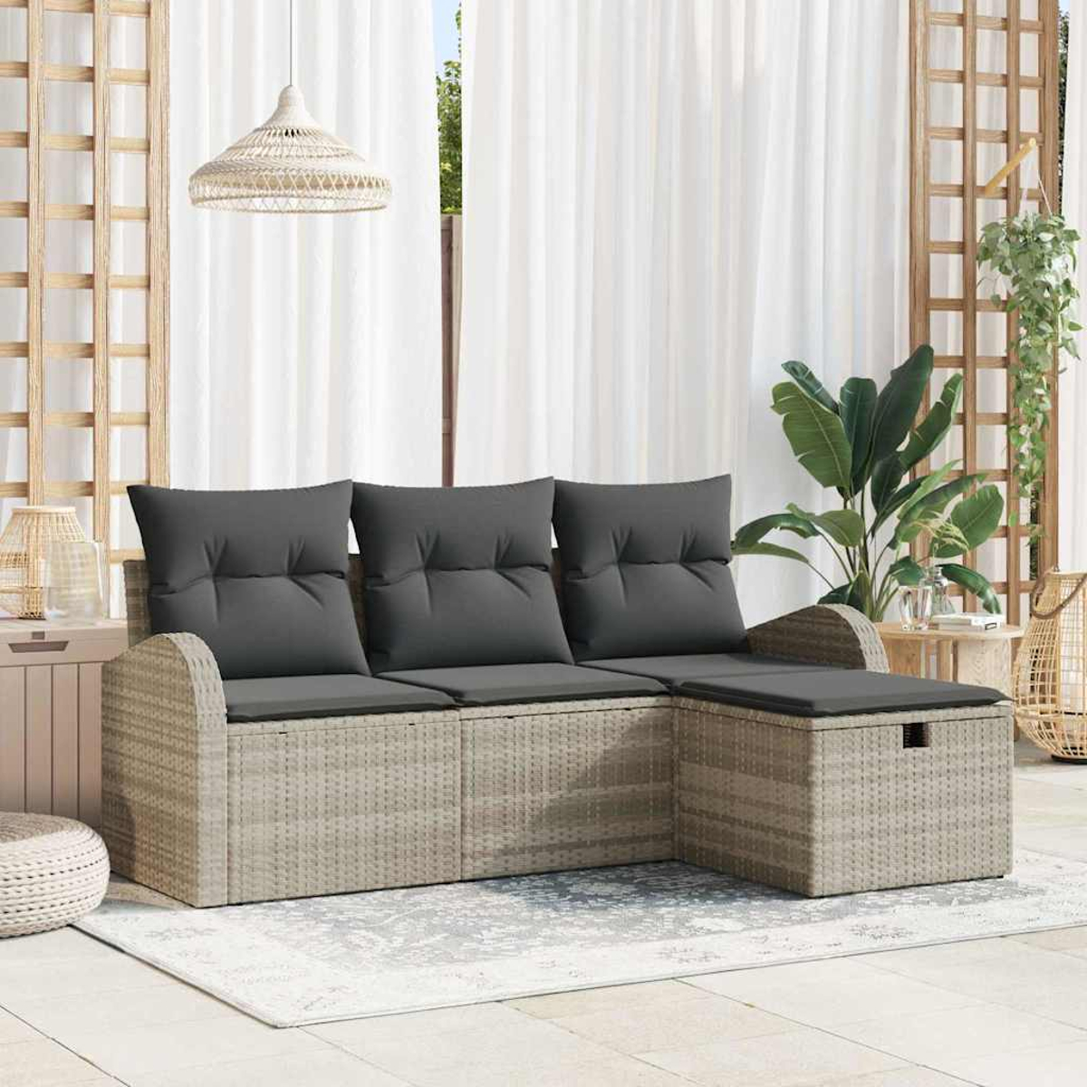 Rattan-Ecksofa mit grauen Kissen. Weiße Vorhänge im Hintergrund. Eine Pflanze und eine Hängelampe sind ebenfalls sichtbar.