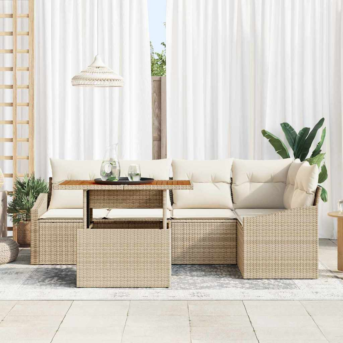 Geflecht-Terrassenmöbel mit cremefarbenen Kissen, einem kleinen Tisch mit Getränken und weißen Vorhängen im Hintergrund.