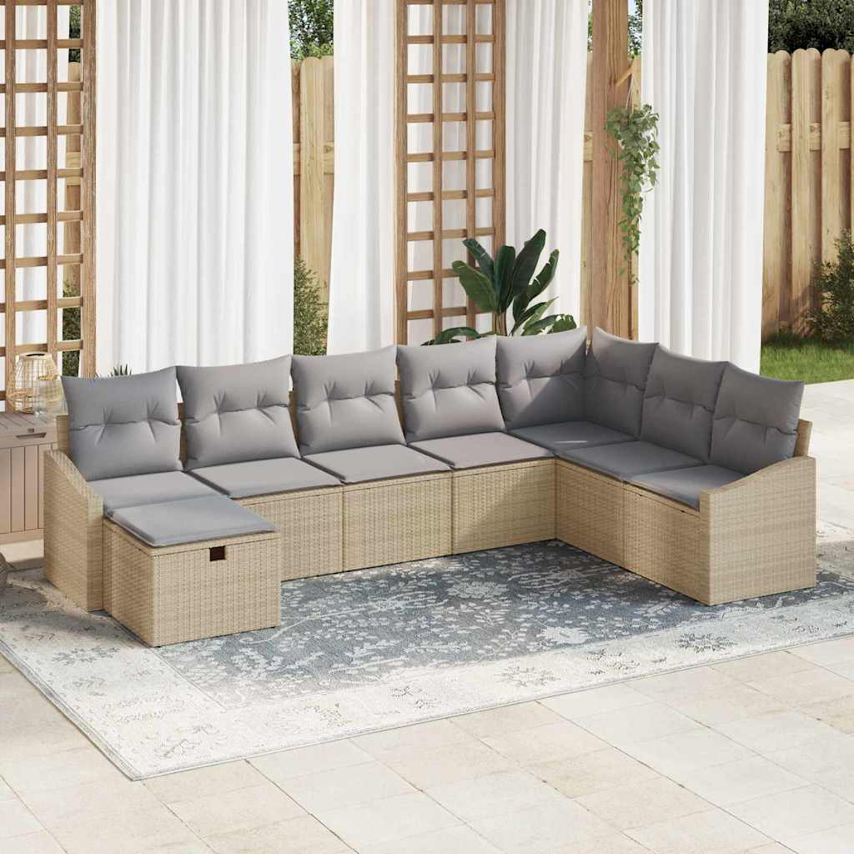 Un sofá seccional exterior con cojines grises está sobre una alfombra. Cortinas blancas y paneles de celosía de madera enmarcan el fondo.