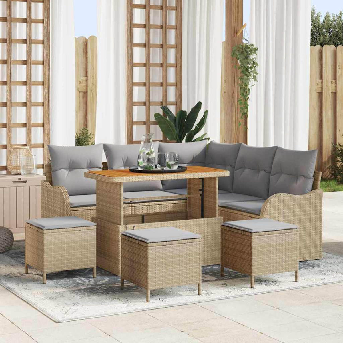 Outdoor-Geflechtmöbel-Set mit Tisch, Sofa und Hockern. Graue Kissen und ein Holztisch. Vorhänge und Holzzaun im Hintergrund.