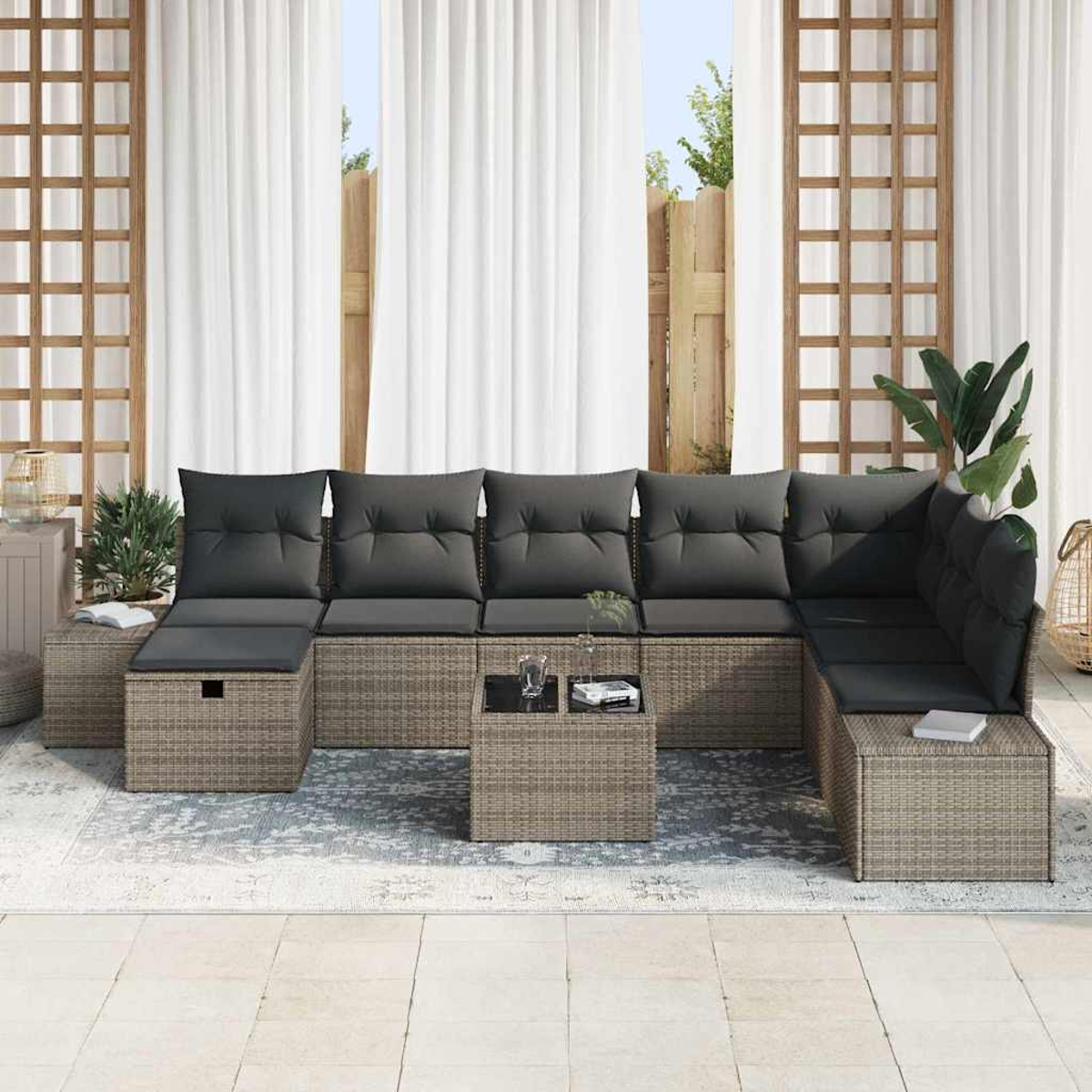 Outdoor-Ecksofa mit grauen Kissen, kleinem Tisch, Pflanzen und weißen Gardinen.