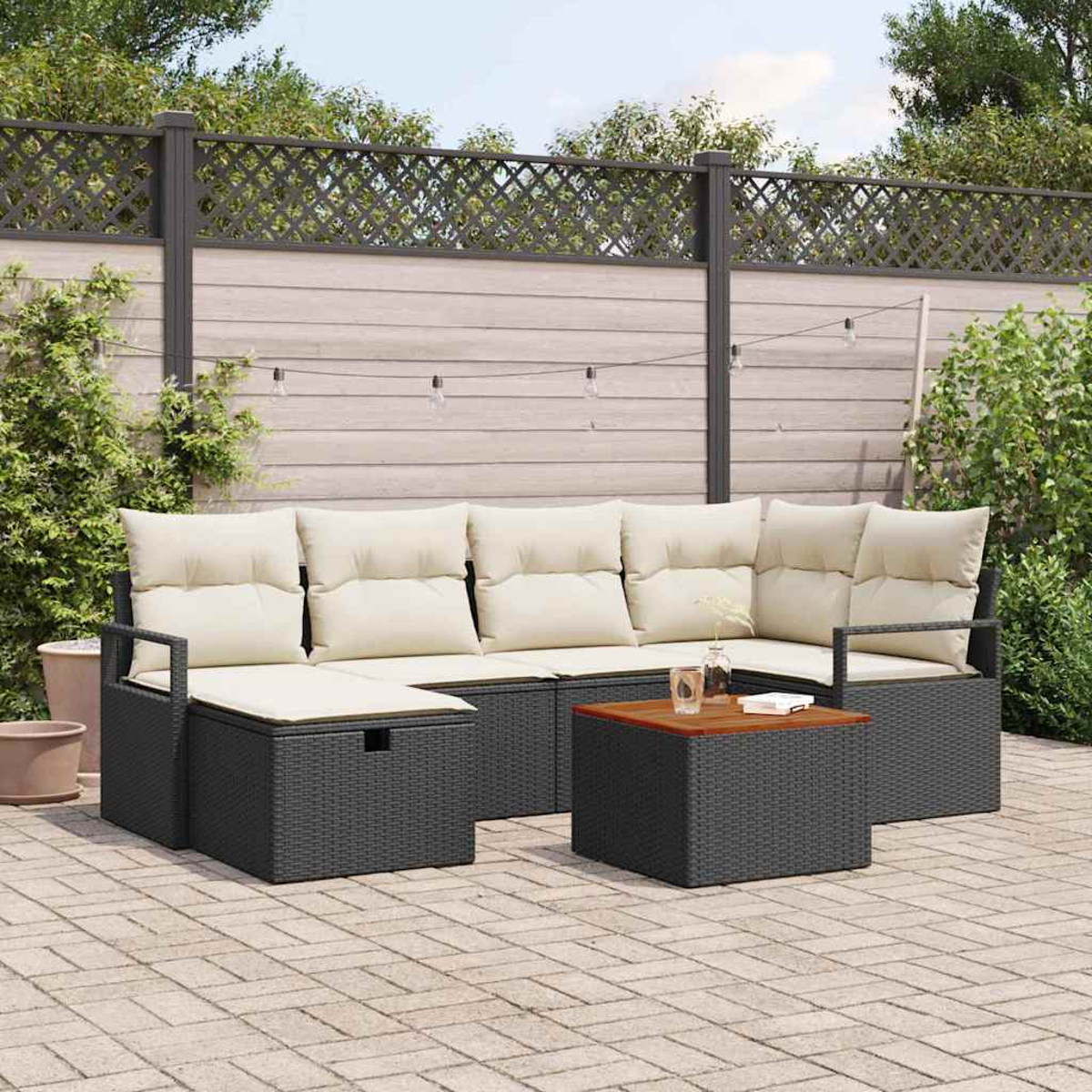 Un sofá seccional de mimbre gris para exteriores con cojines crema y una mesa de centro de madera en un patio pavimentado.