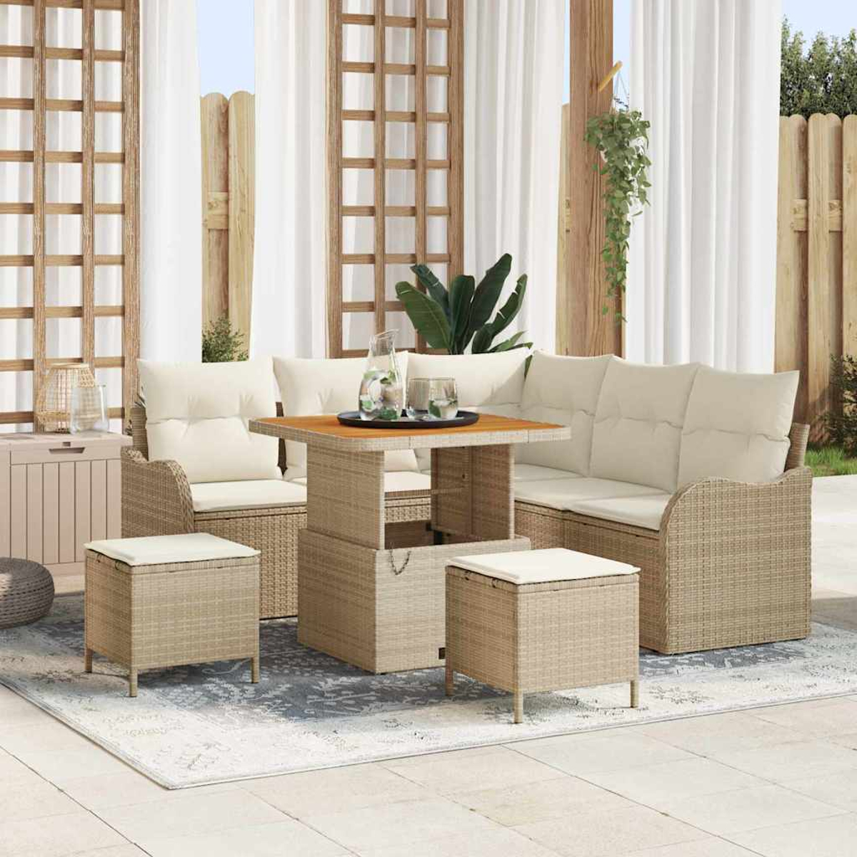 Gartenmöbel-Set aus Korbgeflecht mit beigen Kissen, einem Tisch und zwei Hockern. Weiße Vorhänge und Holzgitter im Hintergrund.