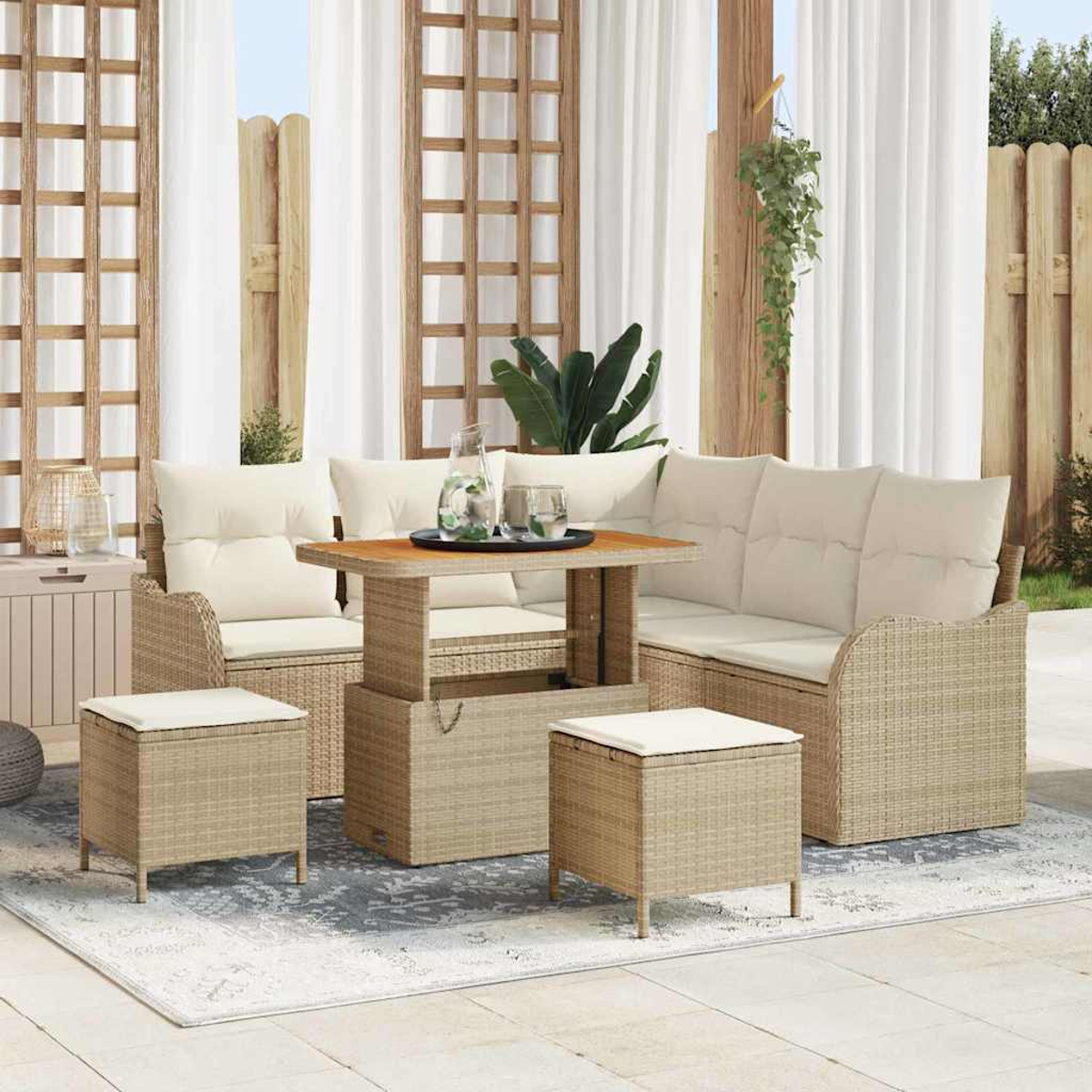 Set di mobili da esterno in vimini con cuscini beige. Include un tavolo, un divano, due sedie e due pouf, su un tappeto fantasia, con tende bianche.