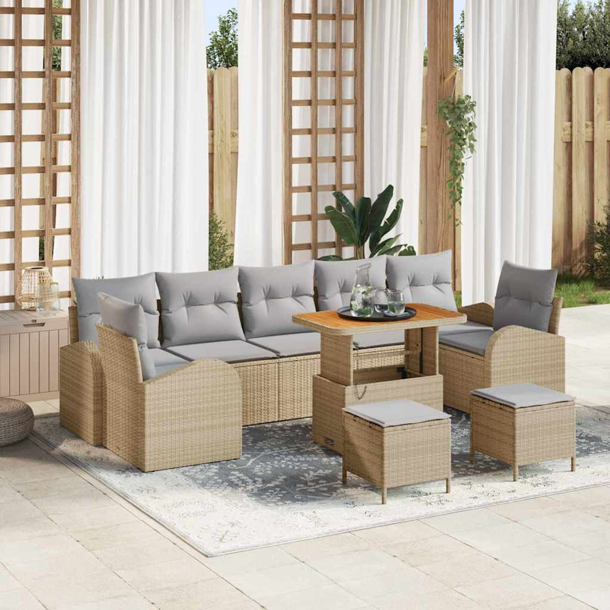 Gartenmöbel-Set aus Korbgeflecht: Sofa, Stühle, Tisch und Hocker, alle mit grauen Kissen, auf einer Terrasse mit Vorhängen und Zaun.