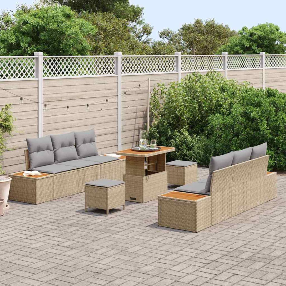 Gartenmöbel-Set: Sofa, Ottomane und ein Tisch mit Hubtisch. Auf einer Backstein-Terrasse mit Zaun und Grün im Hintergrund.