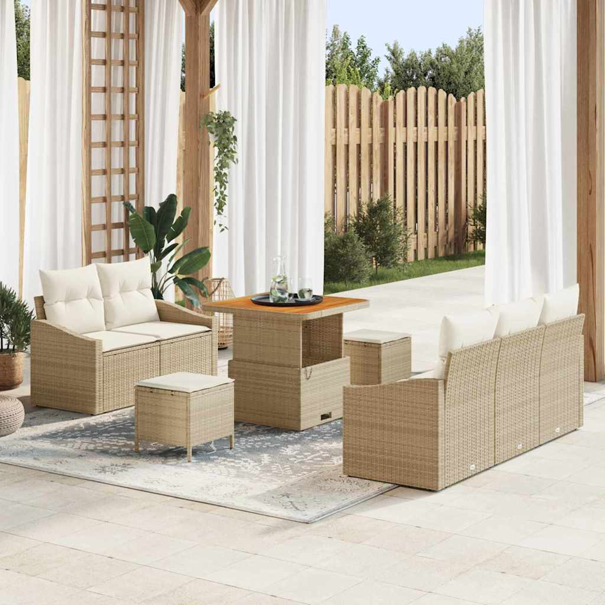 Terrassengarnitur mit beigen Rattanmöbeln und weißen Kissen. Enthält Sofa, Stühle, Tisch und Hocker auf einem gemusterten Teppich.