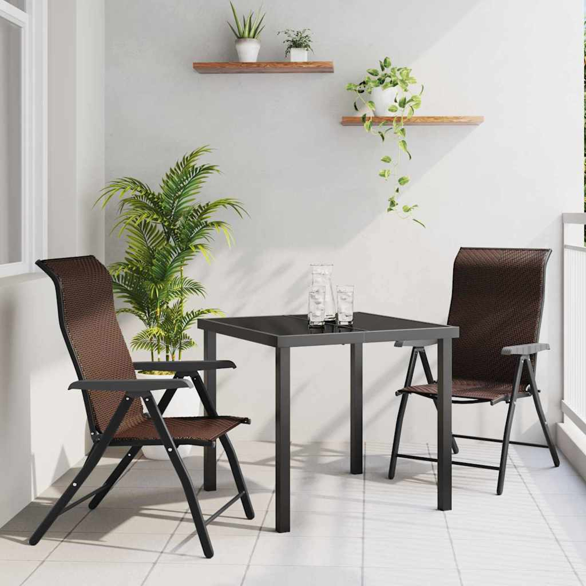 Balkon mit schwarzem Tisch, zwei braunen Stühlen und Pflanzen auf Regalen. Zwei Gläser auf dem Tisch und eine große Pflanze links.
