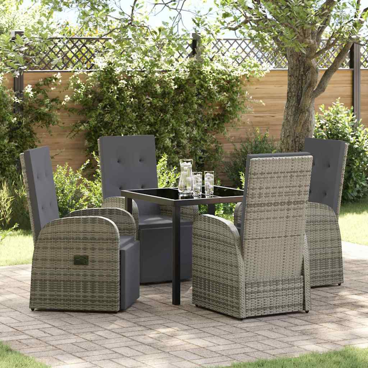 Set da patio all'aperto con sedie grigie attorno a un tavolo nero. Una brocca e bicchieri sul tavolo. Lo sfondo include vegetazione e una recinzione.