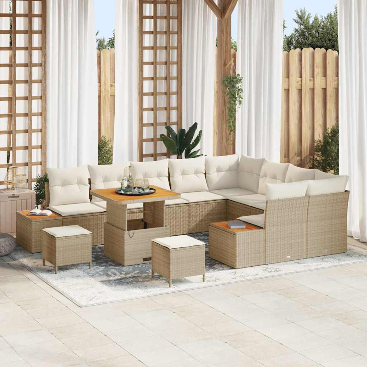 Outdoor-Rattansofa-Set mit beigen Kissen, Couchtisch und Ottomanen. Die Szene umfasst weiße Vorhänge, Holzgitter und Zaun im Hintergrund.