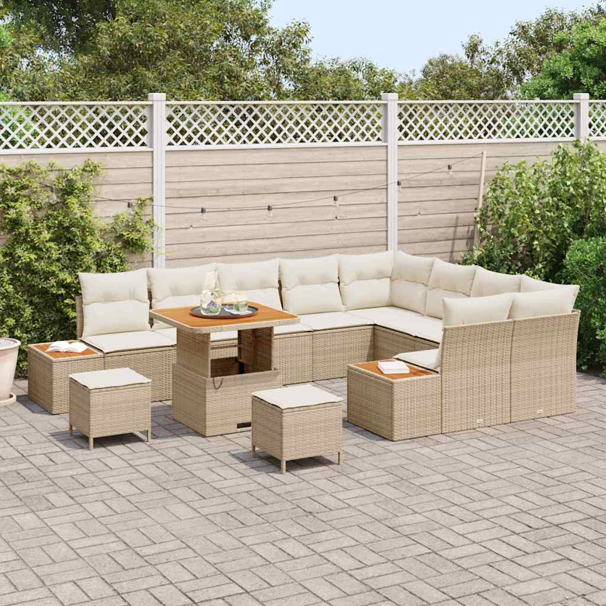Beiges Outdoor-Wicker-Möbelset auf einer Terrasse. Enthält ein Ecksofa, einen Tisch und Hocker. Ein Holzzaun und Grünzeug befinden sich im Hintergrund.
