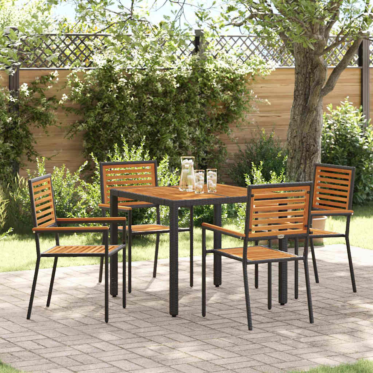 Essgruppe im Freien mit vier Stühlen und einem Tisch. Auf einer Terrasse mit Bäumen und einem Zaun im Hintergrund.