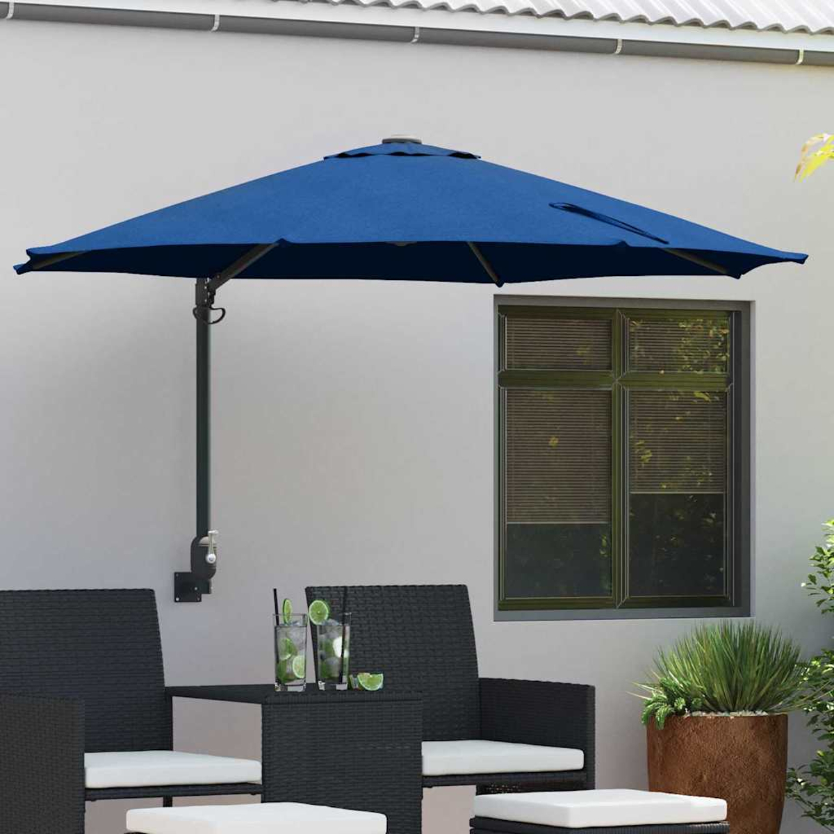 Blauer Sonnenschirm über einem schwarzen Tisch und Stühlen. Getränke mit Limette stehen auf dem Tisch. Fenster und Blumentopf im Hintergrund.