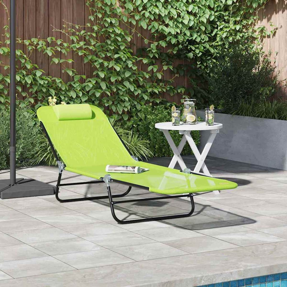 Ein grüner Liegestuhl mit Kissen steht auf einer Terrasse. Ein kleiner weißer Tisch mit Getränken ist in der Nähe. Grünes Laub und ein Holzzaun sind im Hintergrund.