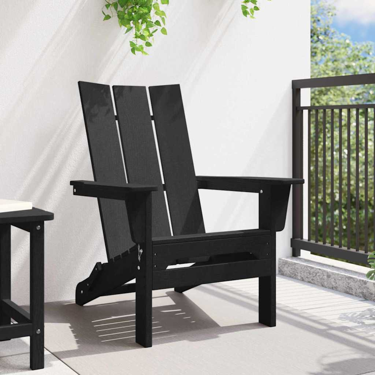 Ein schwarzer Adirondack-Stuhl auf einer Terrasse. Der Stuhl steht neben einem kleinen Tisch. Grüne Pflanzen hängen von der Decke.