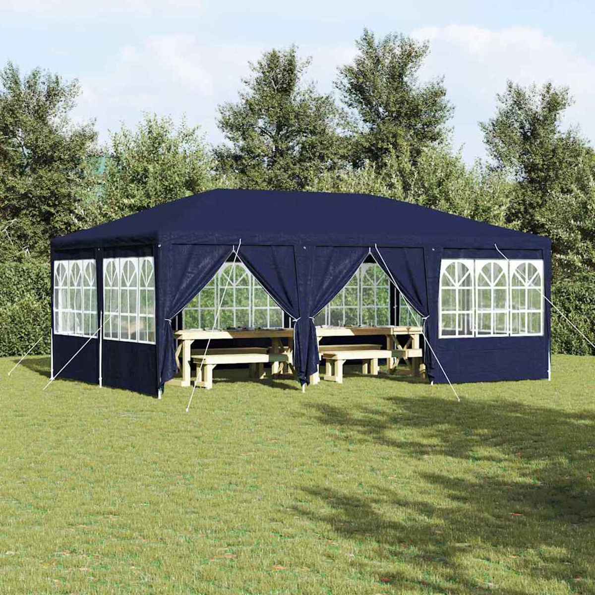 Ein marineblauer Pavillon auf grünem Gras. Innen Holztische und -bänke. Bäume bilden den Hintergrund unter blauem Himmel.