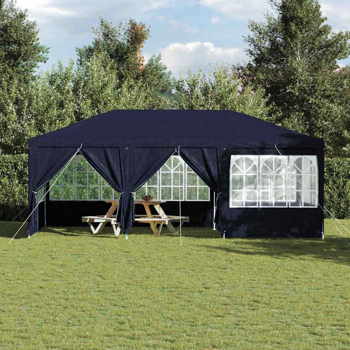 Ein marineblauer Pavillon steht auf Gras. Ein Picknicktisch befindet sich darin. Bäume und Himmel bilden den Hintergrund. Weiße Fensterrahmen sind sichtbar.