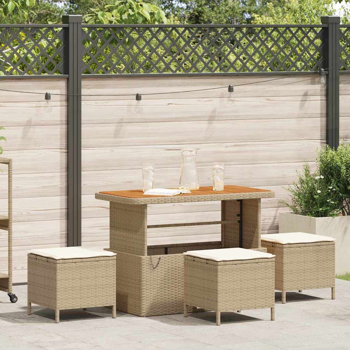 Terrassenset im Freien. Tisch mit Gläsern und Krug, drei Sitzwürfel mit Kissen. Holzzaun im Hintergrund.
