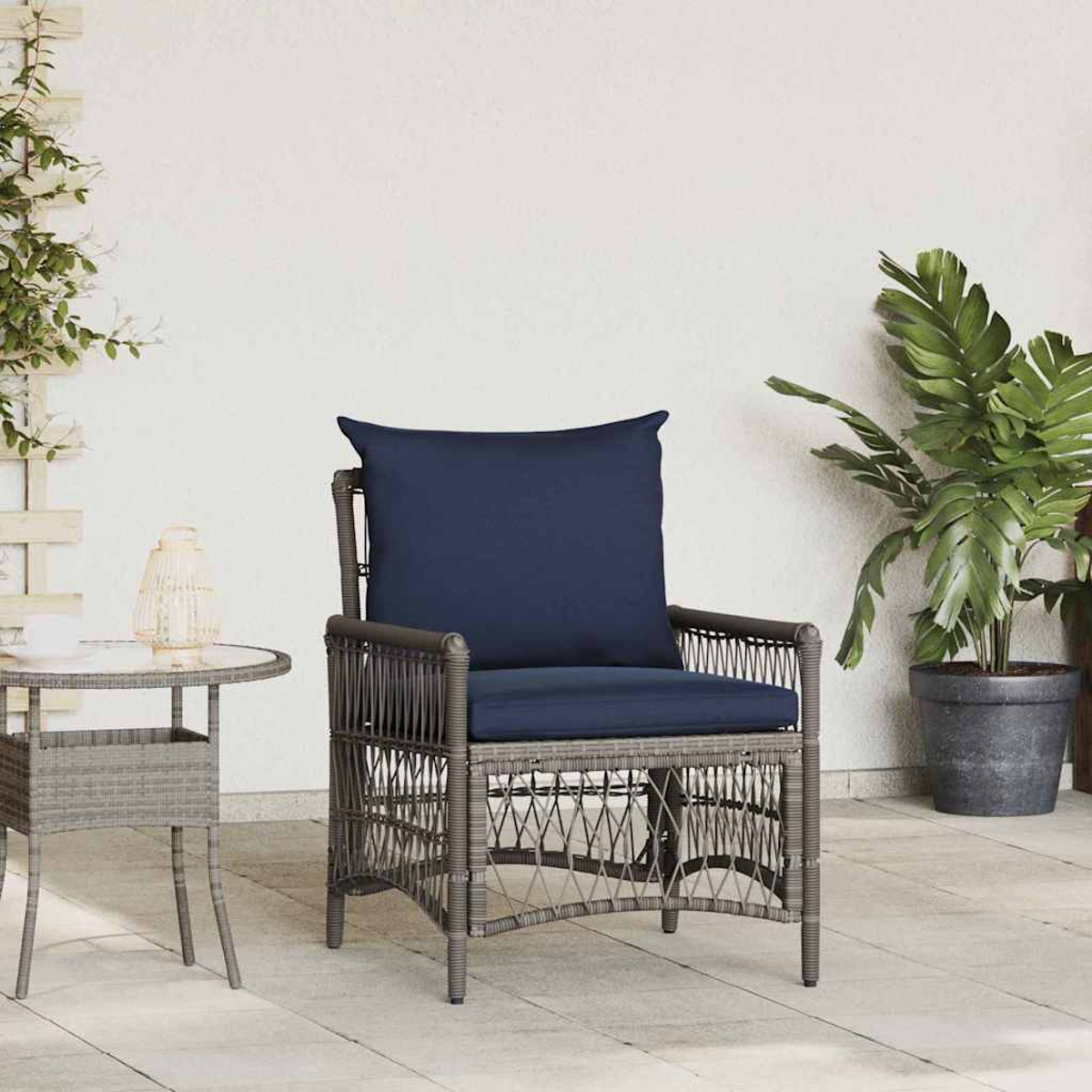 Una silla de mimbre con cojín y almohada azul marino está en un patio. Una mesa auxiliar y una planta en maceta están detrás.