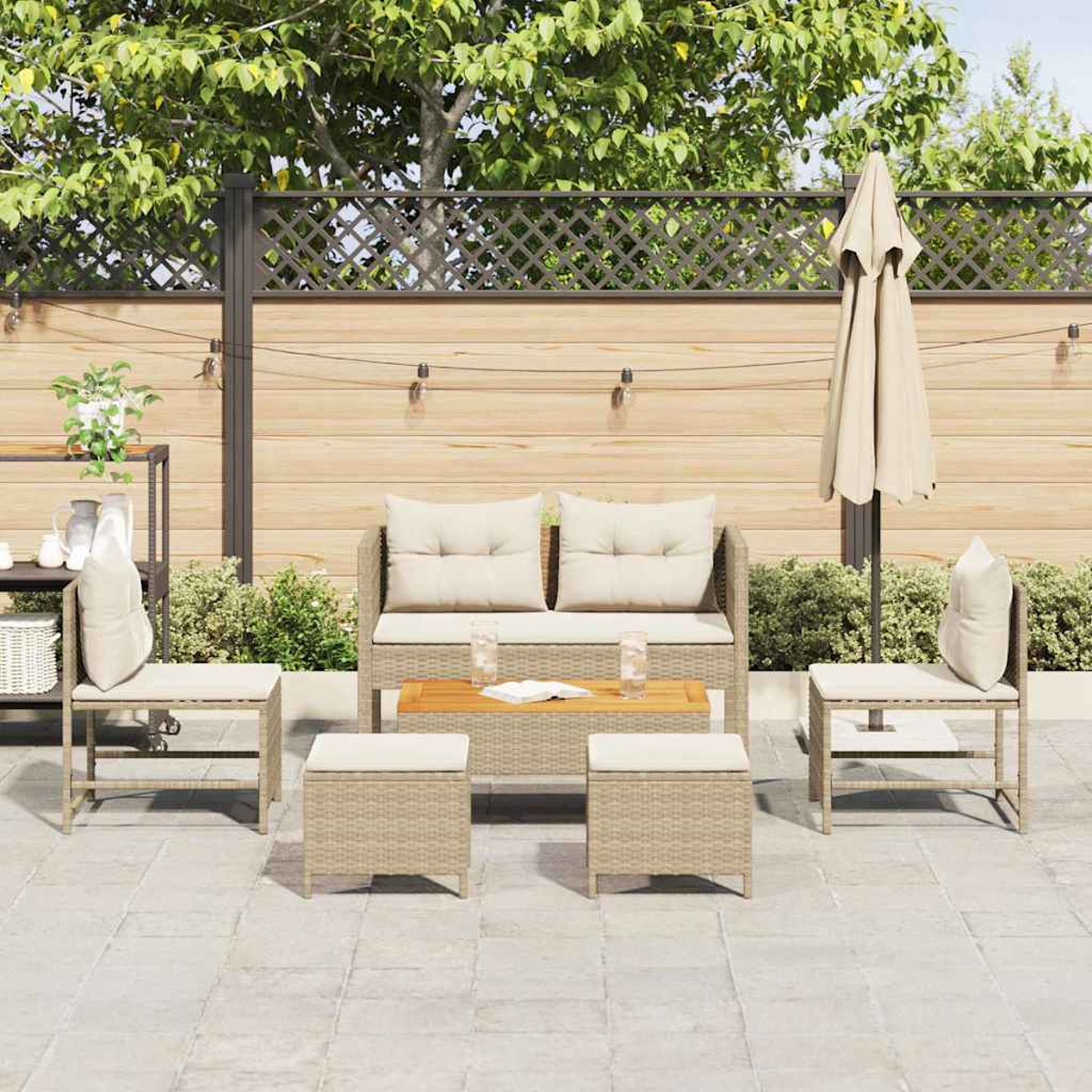 Terrassenset mit Sofa, Stühlen und Tisch. Beige Kissen, Sonnenschirm und Holzzaun. Grüne Pflanzen und Bäume im Hintergrund.