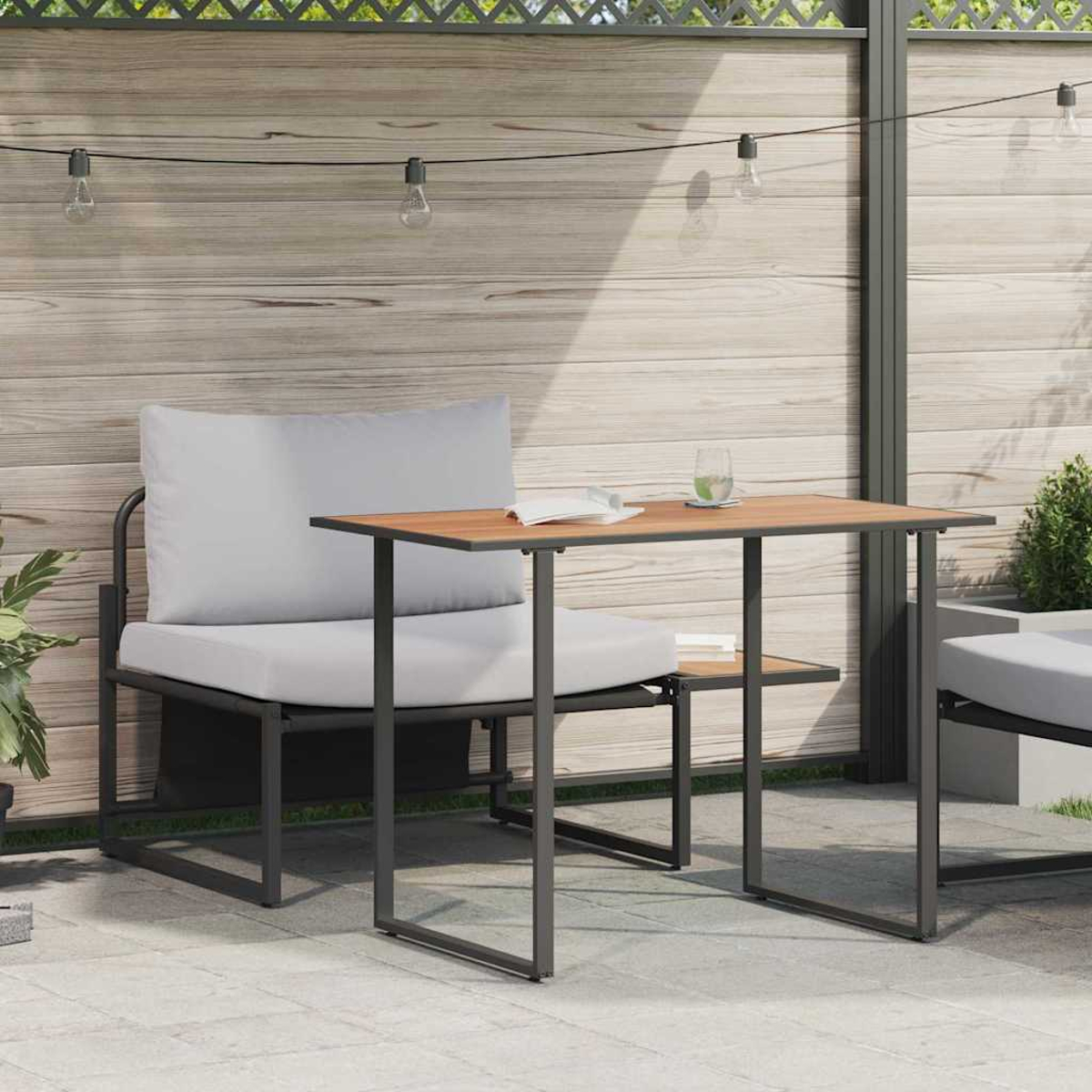 Szene auf der Terrasse im Freien. Grauer Stuhl und Tisch mit Kissen. Auf dem Tisch liegen ein Buch und ein Glas. Holzzaun und Lichterketten im Hintergrund.